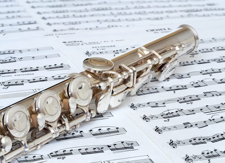 A silver concert flute resting on sheet music